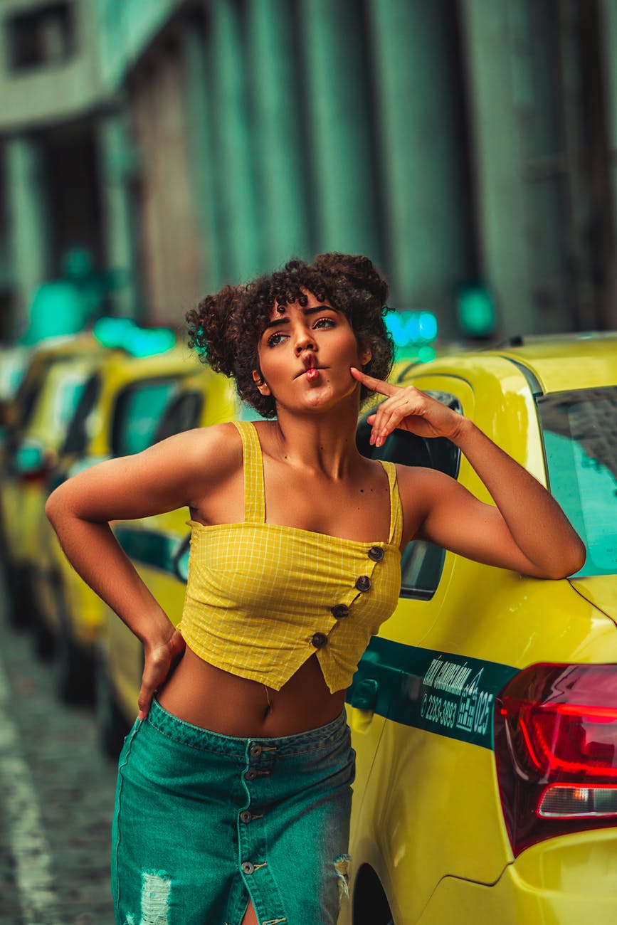 selective focus photography of woman pouting her lips while leaning on taxi