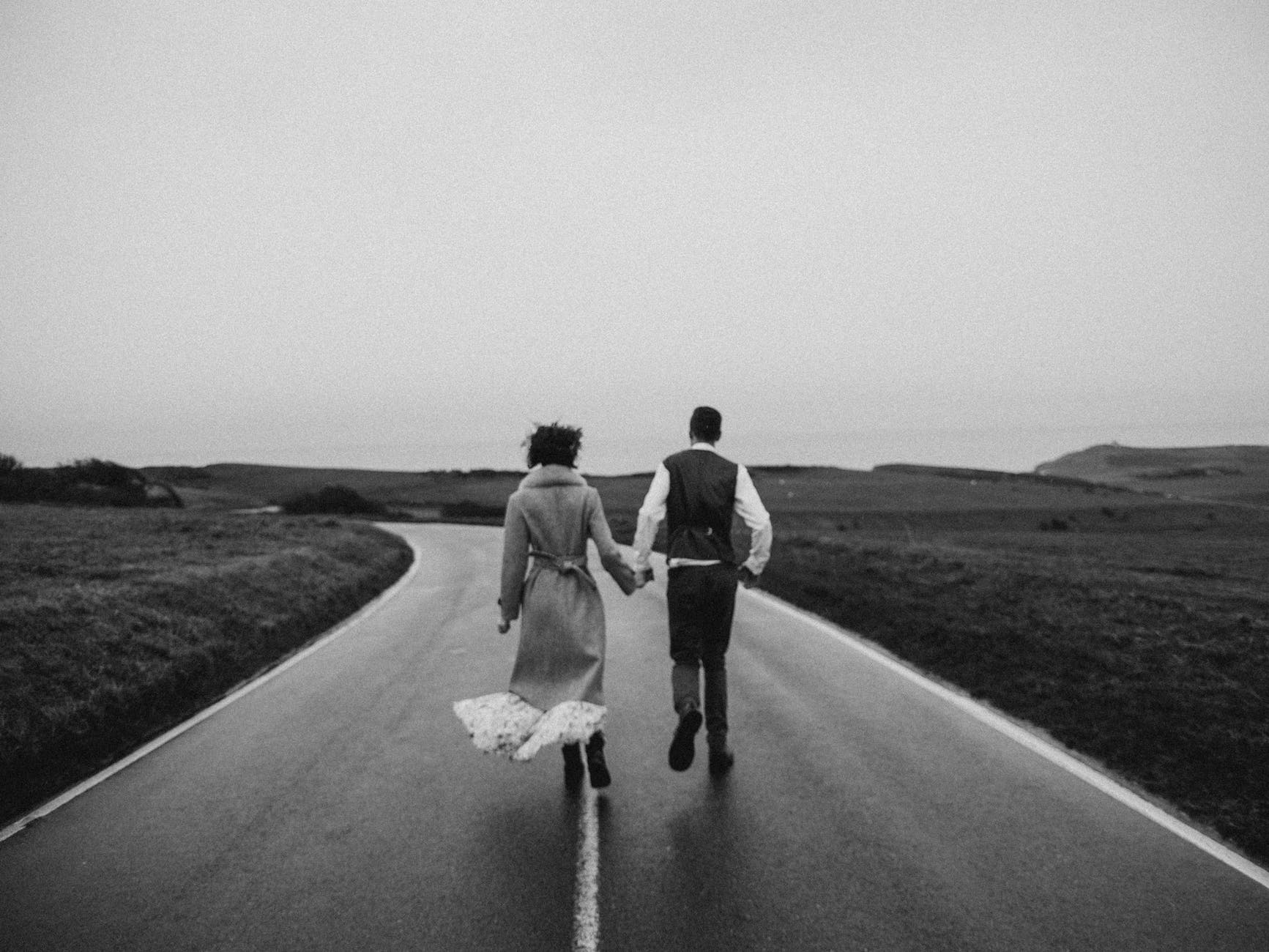 grayscale photo of couple walking on road
